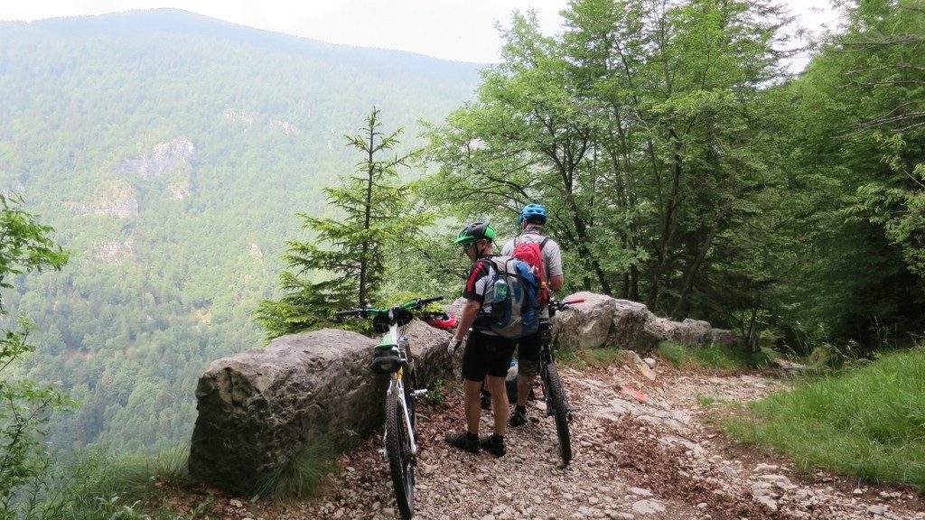 zwei Mountainbiker schauen von einem steinigen Weg aus ins Val Torra