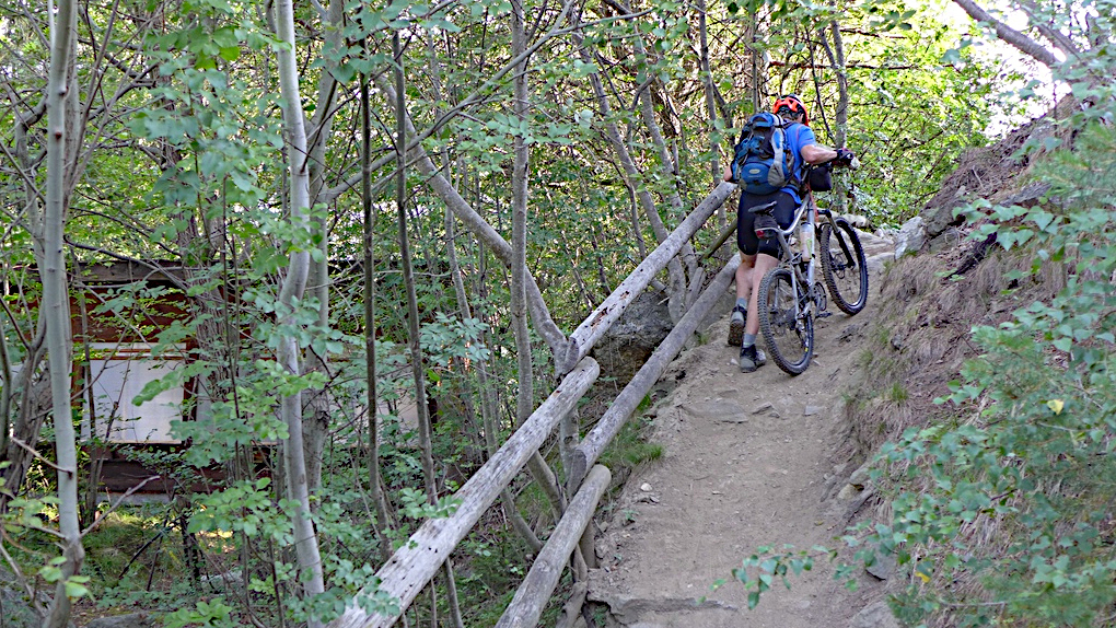 Ein Mountainbiker schiebt sein Rad einen Weg über dem Marteltal im Vinschgau hoch