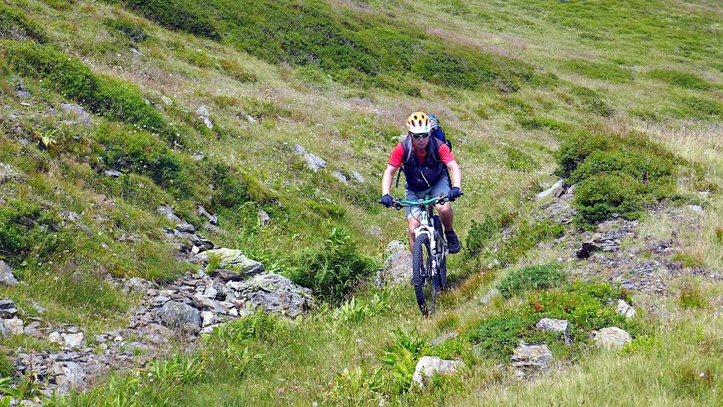 ein Mountainbiker für über einen steinigen Wiesenweg Richtung Gossensaß ab